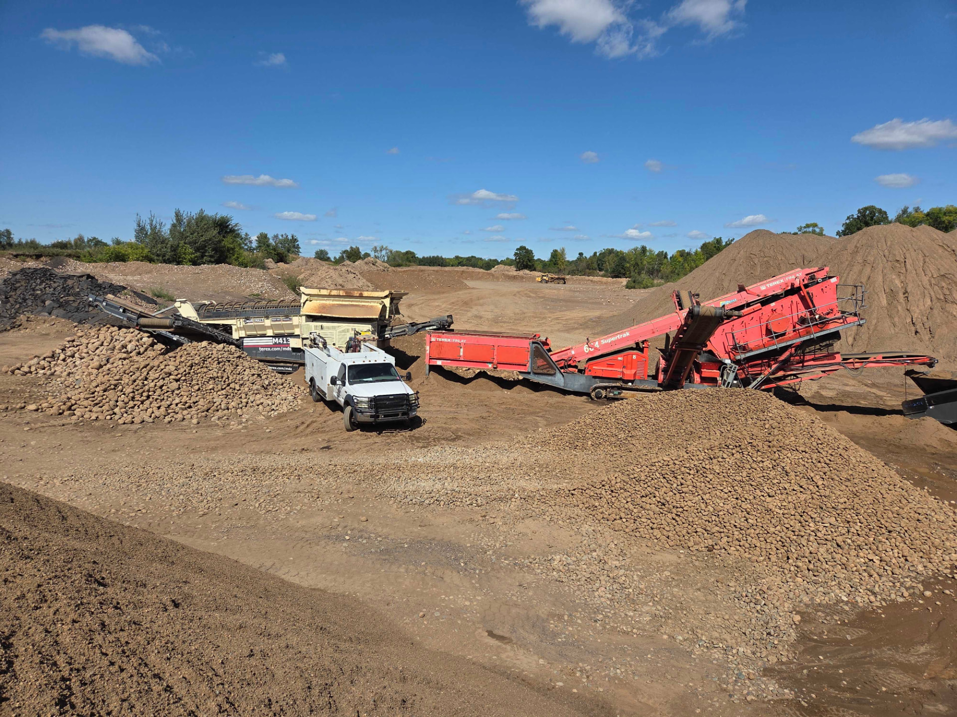 Mobile welding truck between Terex Finlay 883+ screener and Supertrak conveyor at a gravel quarry