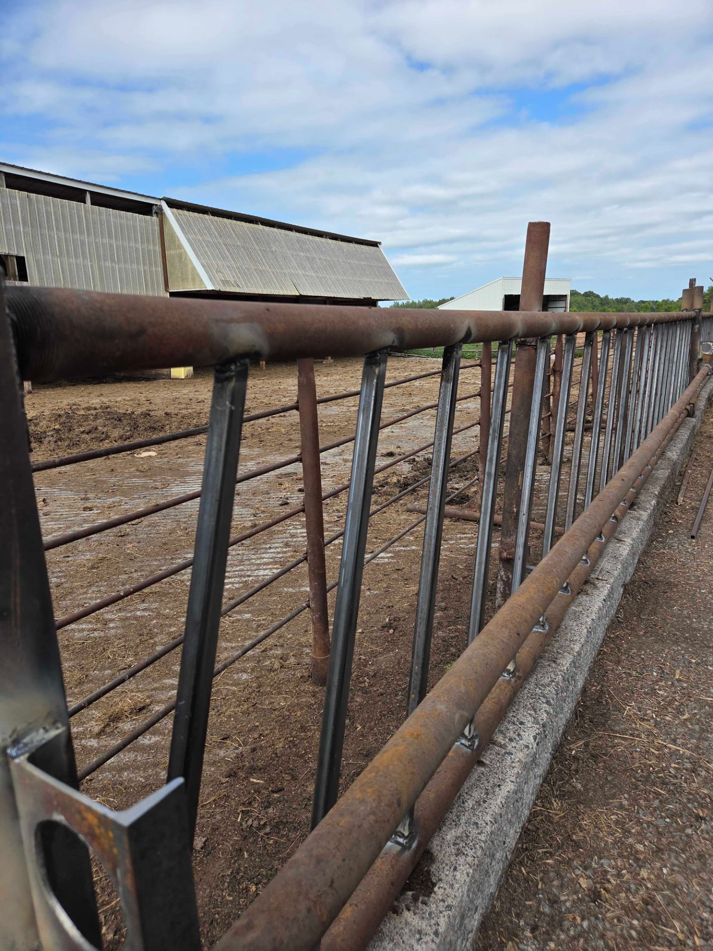 Welded steel livestock fence rails repaired in front of a barn